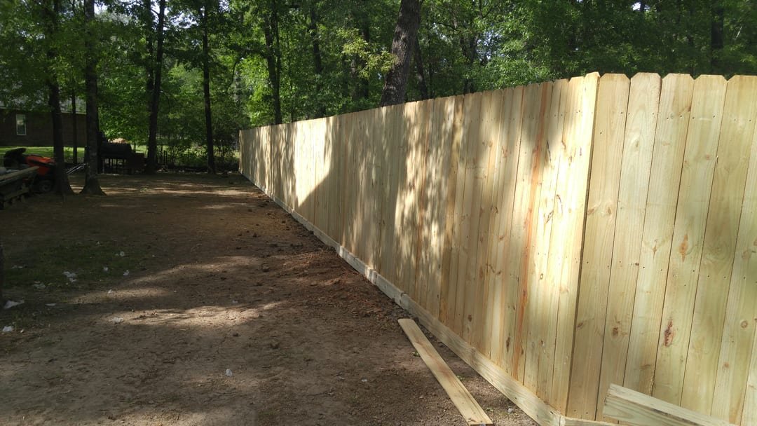 Finished cedar privacy fence with a rot board along a backyard